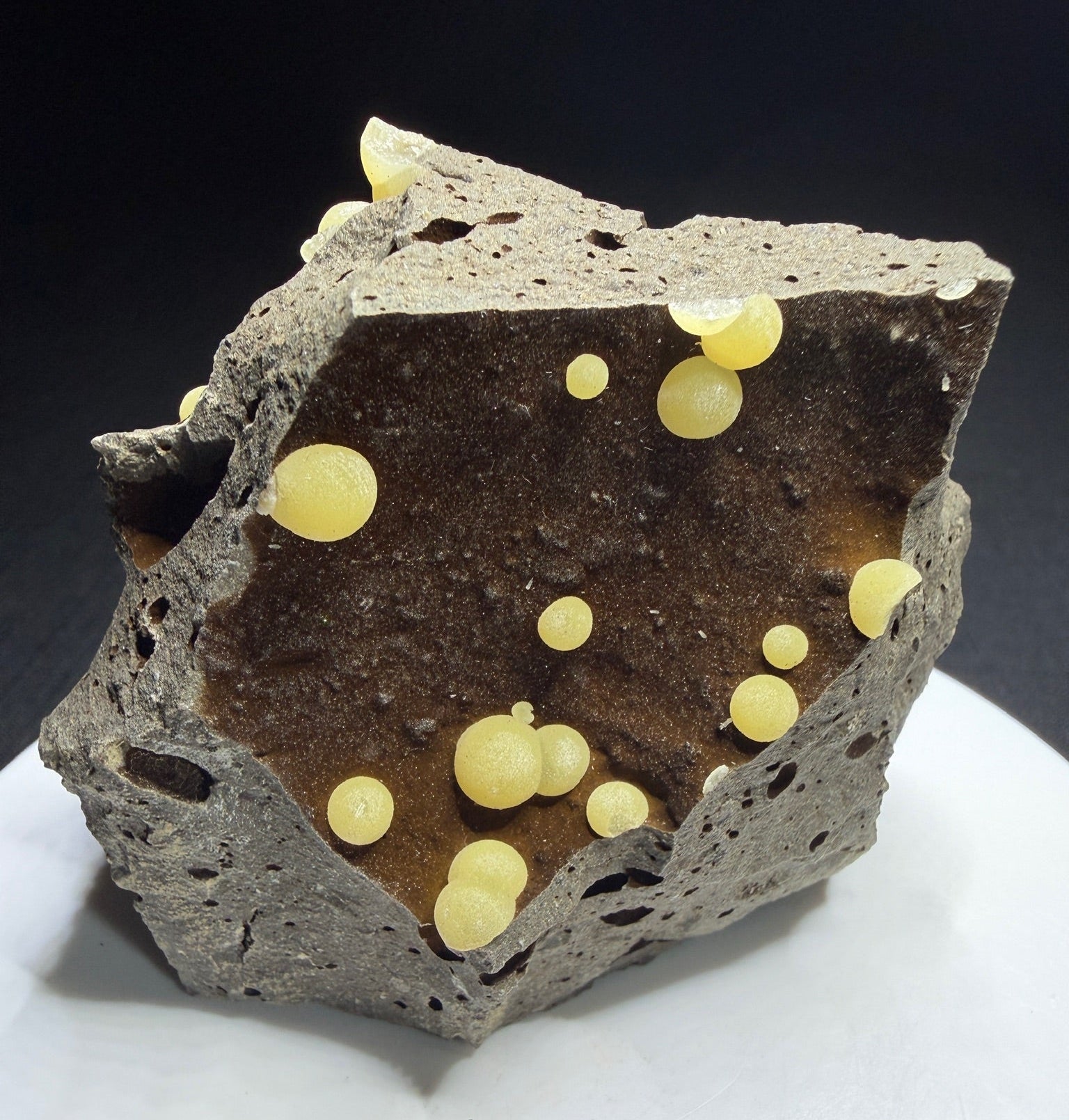 Pale yellow spherical calcite aggregates in a basalt cavity from Campomorto Quarry, Italy.