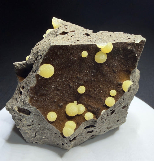 Pale yellow spherical calcite aggregates in a basalt cavity from Campomorto Quarry, Italy.