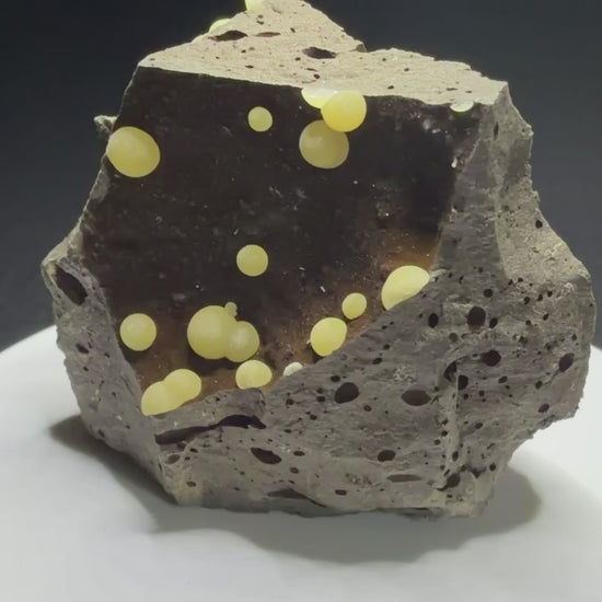 Pale yellow spherical calcite aggregates in a basalt cavity from Campomorto Quarry, Italy.