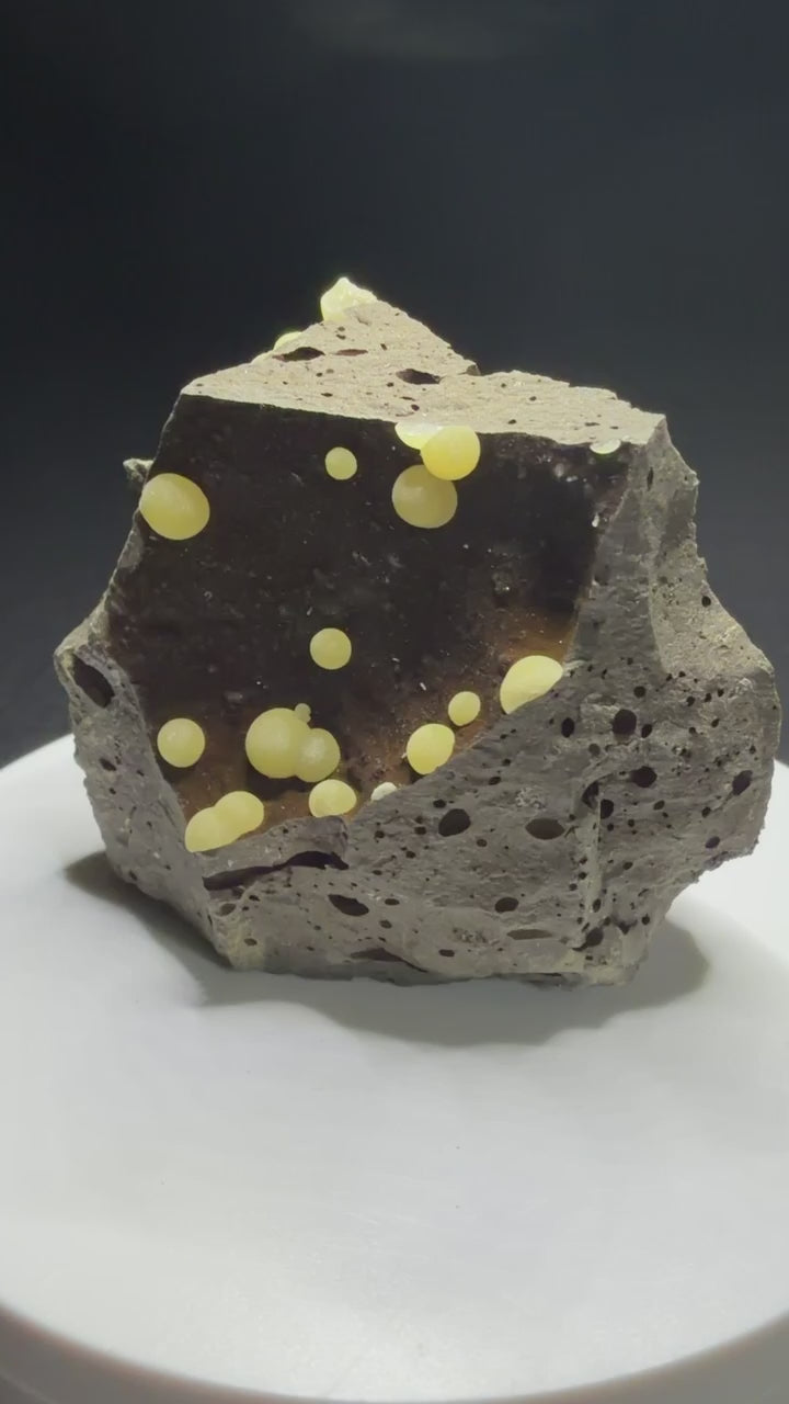Pale yellow spherical calcite aggregates in a basalt cavity from Campomorto Quarry, Italy.