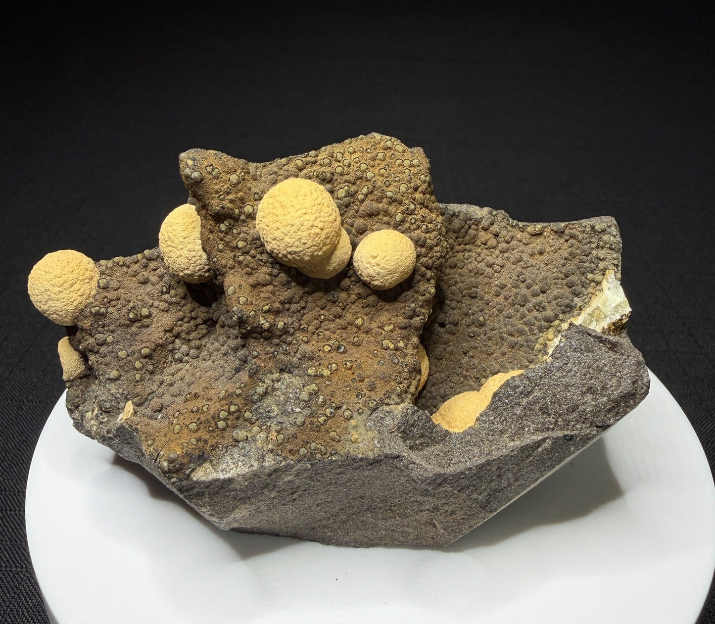 Pale yellow spherical calcite formations on dark basalt from Zhejiang Province, China